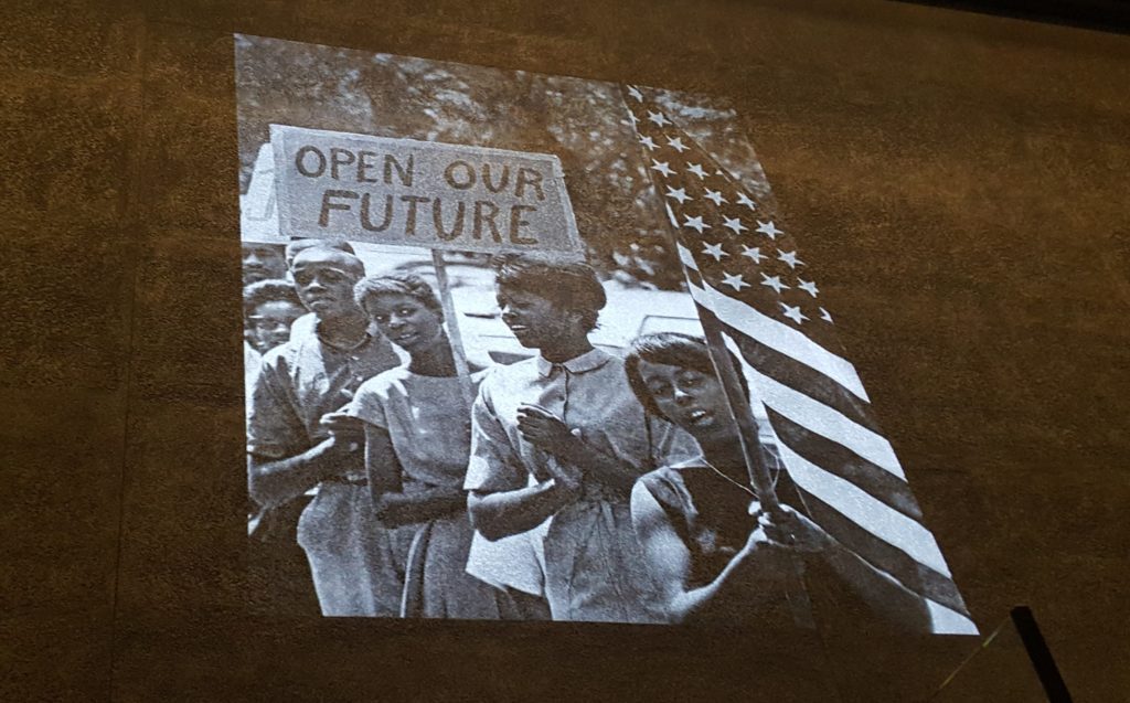 A projector displays images above the "Defending Freedom, Defining Freedom" exhibits.